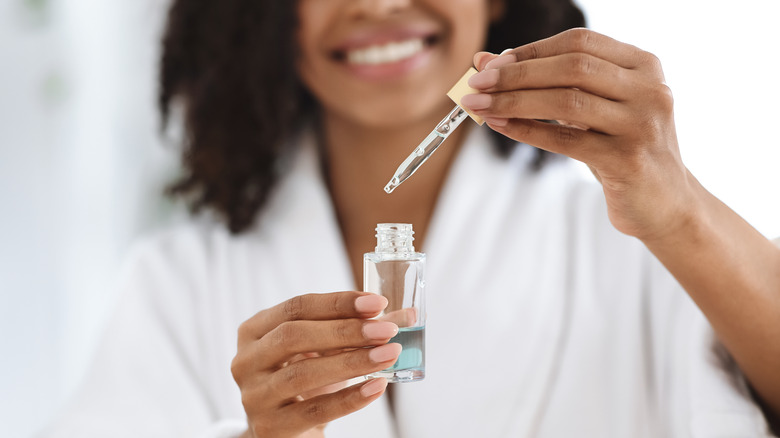 Smiling woman holding a dropper and bottle 