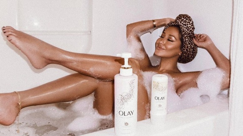 Adrienne Bailon sitting in the bathtub using Olay products