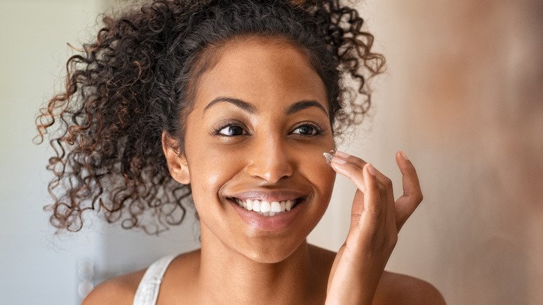Woman smiling and applying skincare