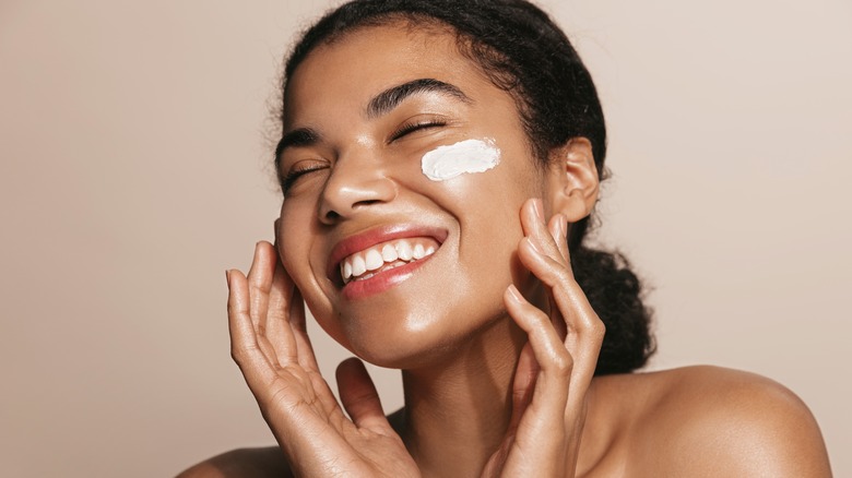 woman smiling putting moisturizer on