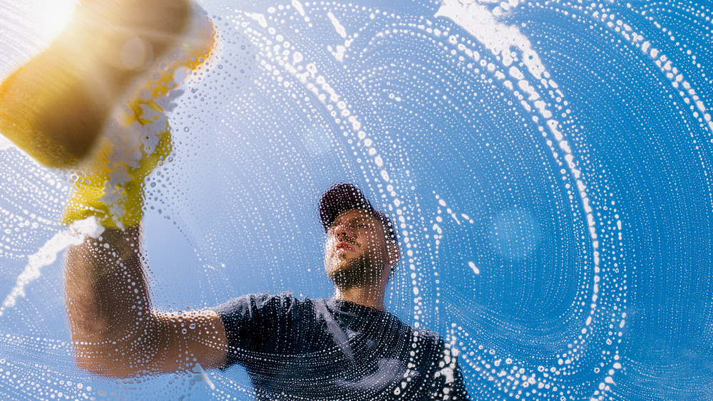 A man washing windows with a sponge 