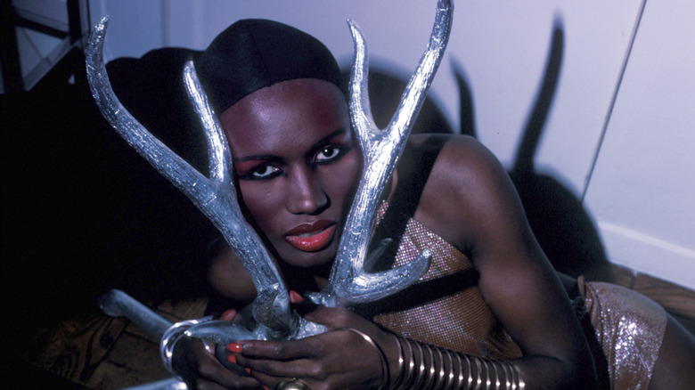 Grace Jones poses for a portrait holding silver antlers