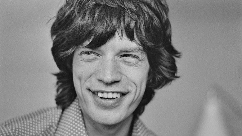 Mick Jagger smiles in a black and white headshot