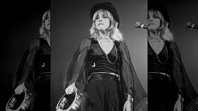 Stevie Nicks plays the tambourine onstage in a black outfit