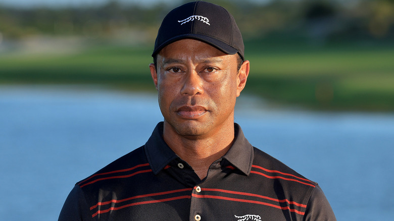 Tiger Woods looking forward with a neutral expression in a black hat