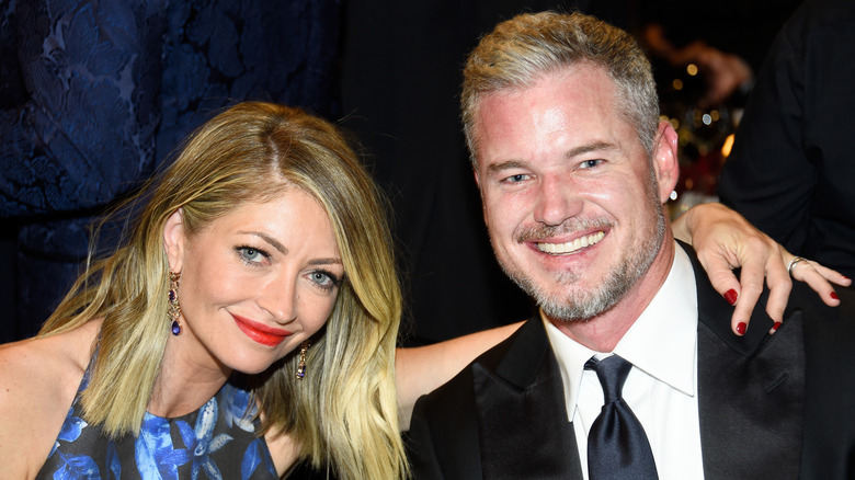 Rebecca Gayheart sitting with her arm around Eric Dane as he smiles