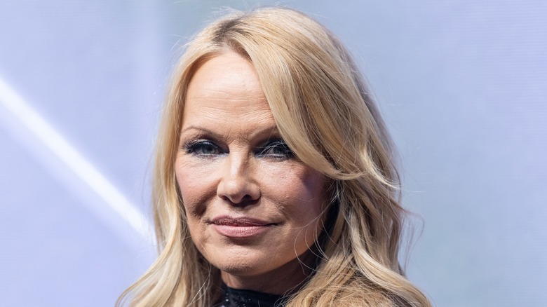 Pamela Anderson smirking in a black outfit at the HM Hunger