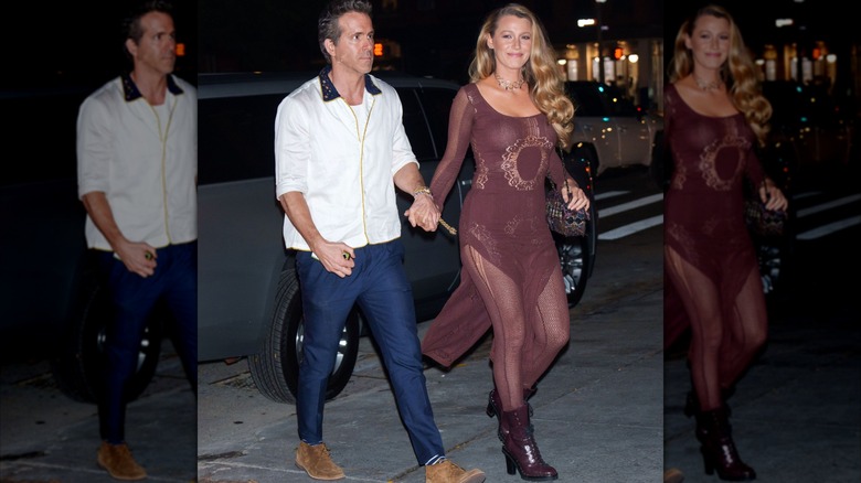 Blake Lively on the street at night, holding hands with Ryan Reynolds and wearing a burgundy sheer dress over sheer leggings with above-ankle, lace-up boots
