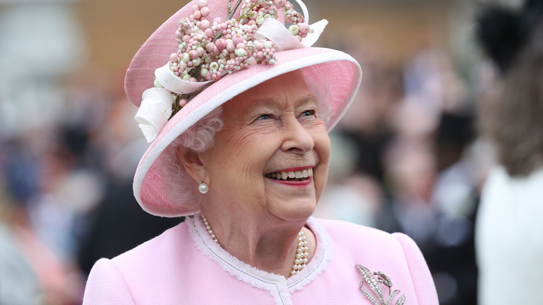 Queen Elizabeth II laughing in an all-pink outfit