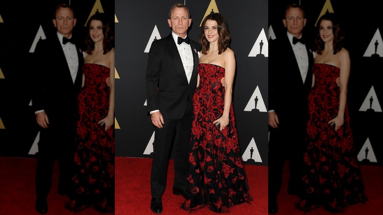 Daniel Craig in a suit and Rachel Weisz in a red floral dress at an event together