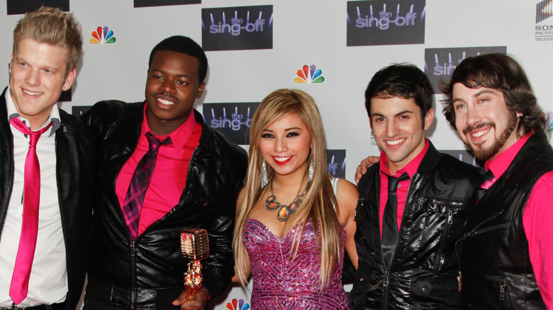 Kirstin Maldonado with straight, blond hair posing between her four bandmates at "The Sing-Off" live season finale in 2011