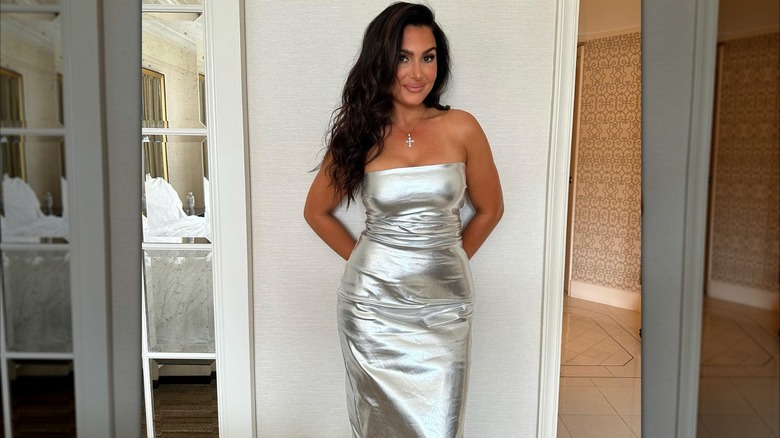 Molly Qerim posing against a white wall in a silver dress.