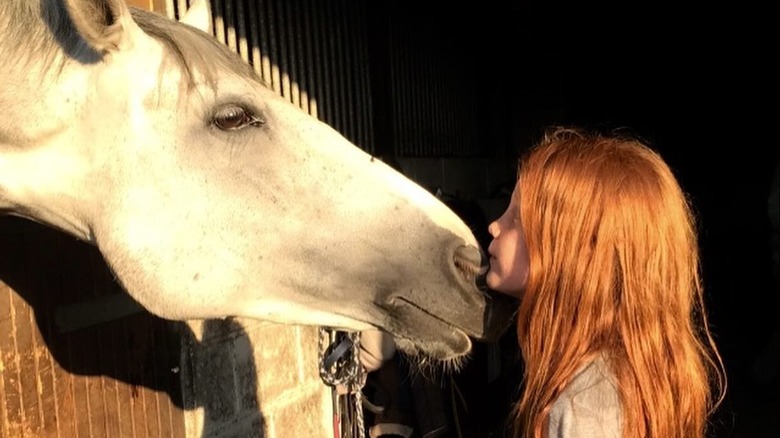 Phoenix Jopling as a young child kissing a horse