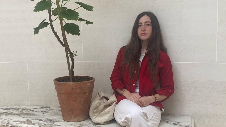 Angelica Jopling sitting next to a plant in a red shirt with her hair down