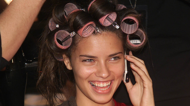Adriana Lima laughing on phone with rollers in her hair