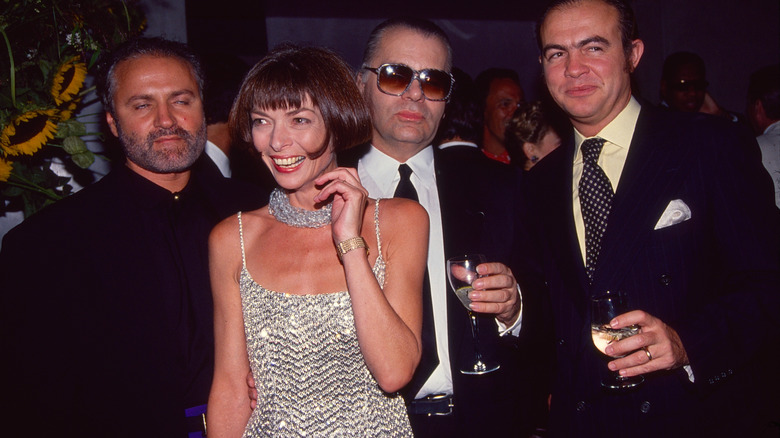 Anna Wintour smiling while surrounded by fashion icons at Fashion Week 1990