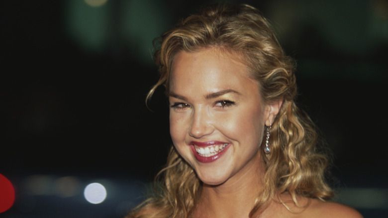 Arielle Kebbel smiling outside at night with her hair half down in curls