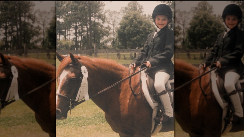 A young Arielle Kebbel sitting in riding gear on a horse as a child