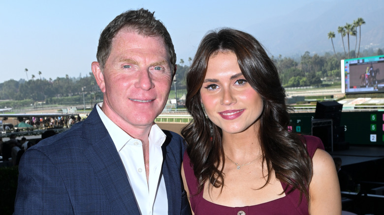 Chef Bobby Flay and his daughter Sophie smile outside in front of a race track