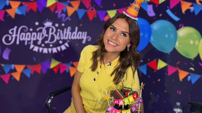 Sophie Flay smiles wearing yellow and a birthday hat at her 30th birthday celebration at work.