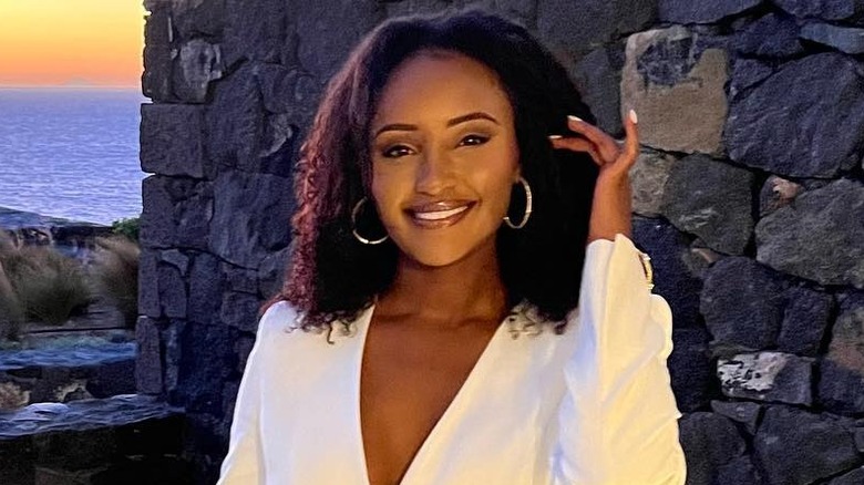 CNN's Rahel Solomon stands in front of a sunset wearing white
