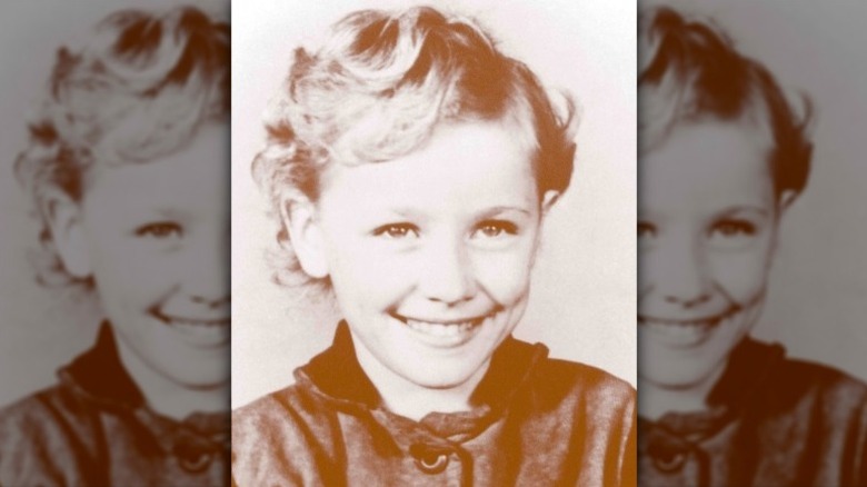 A young Dolly Parton smiling in a sepia photo