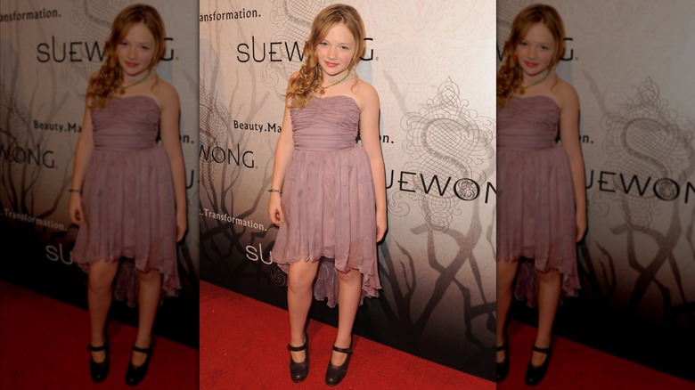 Natalie Alyn Lind posing in a dusty rose dress.