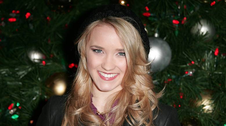 Emily Osment smiling in front of Christmas tree in 2009