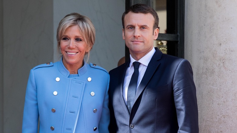 Brigitte and Emmanuel Macron smiling for photo outside a building