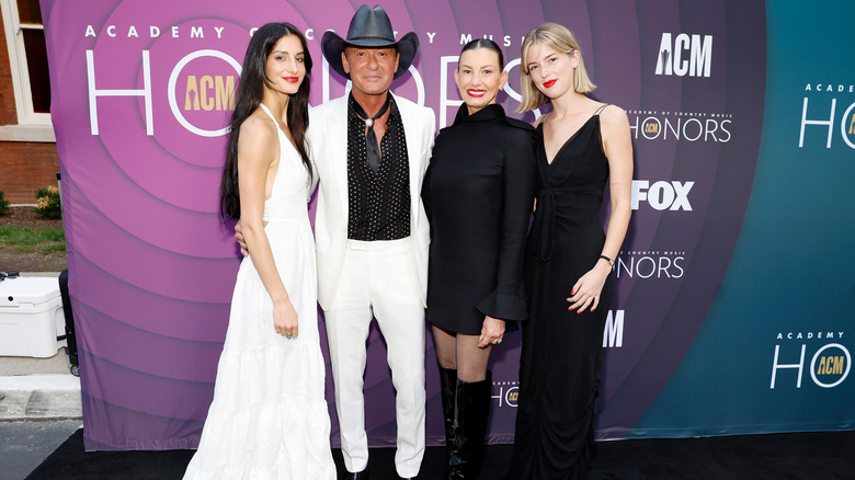 Tim McGraw and Faith Hill posing with their daughters