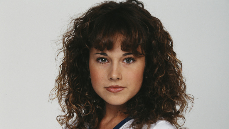 A young Nikki DeLoach  with curly hair poses against a white background wearing a white t-shirt