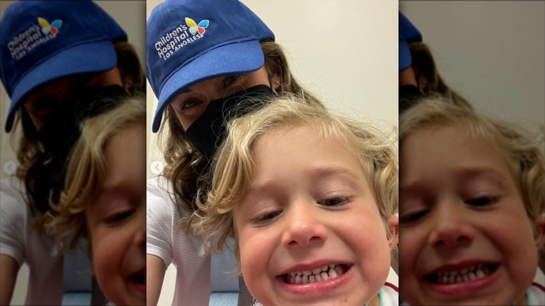 Nikki DeLoach wearing a face mask and CHLA hat in a selfie with her son