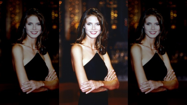 Heidi Klum smiling and posing with her arms folded on a talk show in 1997