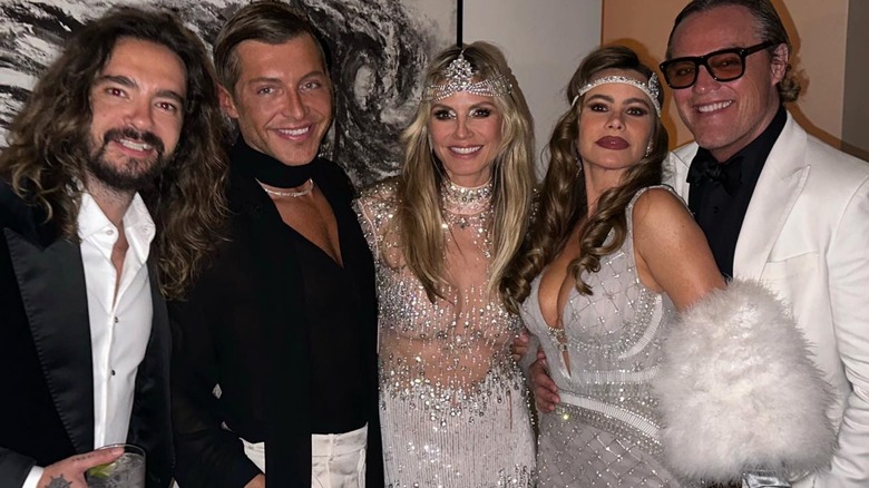 Heidi Klum, center, in a silver dress with friends at her 50th birthday party, all smiling