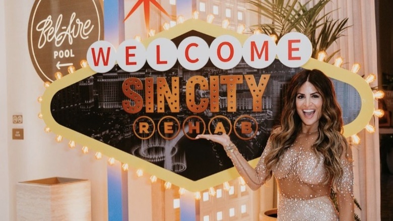 Alison Victoria posing in front of Sin City Rehab logo