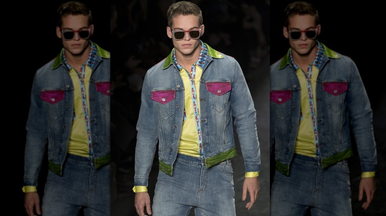 Mitchell Slaggert on the catwalk in sunglasses, jeans, denim jacket, and a yellow shirt