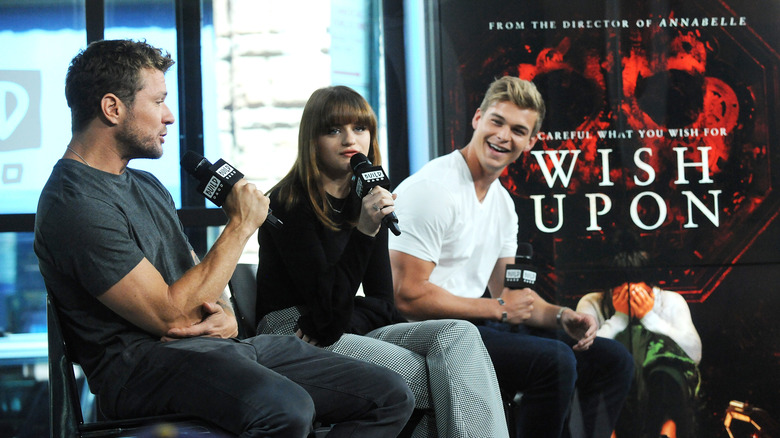 Mitchell Slaggert holding a mic and smiling with costars Ryan Phillippe and Joey King
