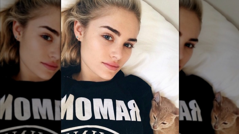 A 2017 selfie of Michelle Randolph lying on a bed with a cat.