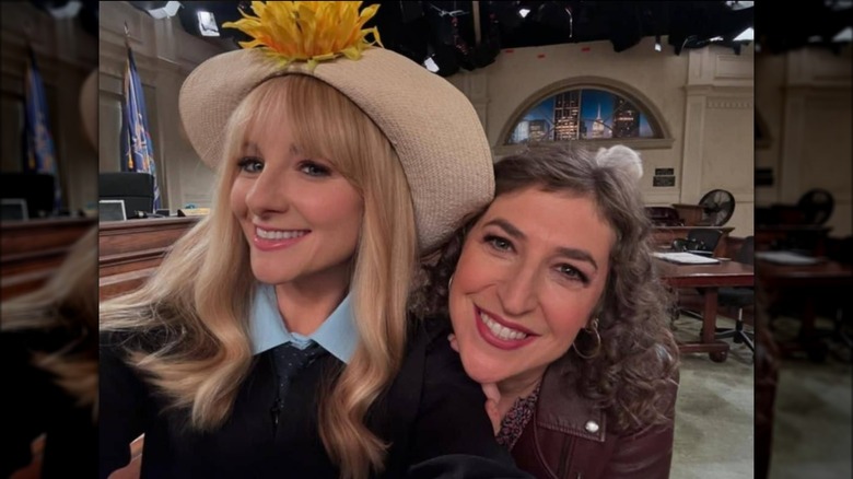 Melissa Rauch wearing a sunflower hat and taking a selfie with Mayim Bialik on the Night Court set