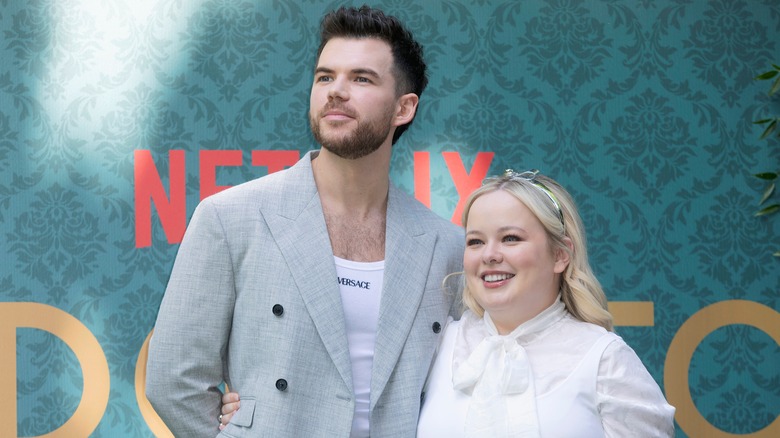 Nicola Coughlan in white with costar Luke Newton in gray blazer and white shirt