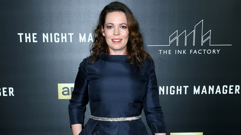 Olivia Colman smiles with her hair down in a dark dress at a premiere of "The Night Manager"