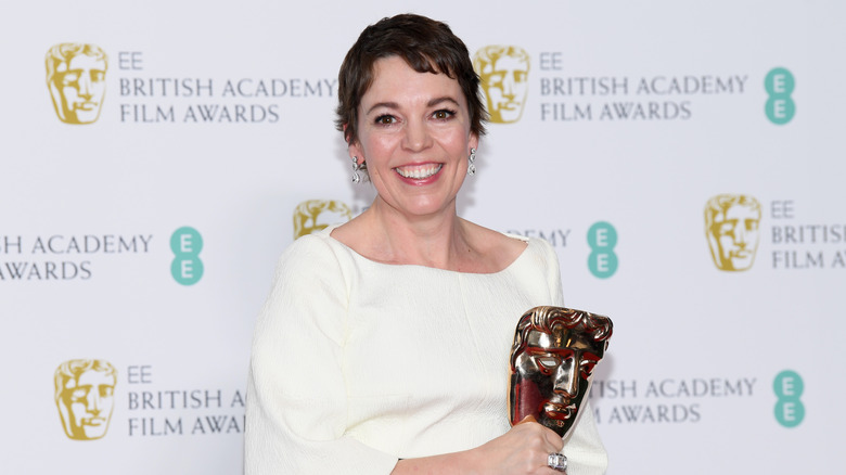 Olivia Colman smiles while holding her BAFTA award in 2019