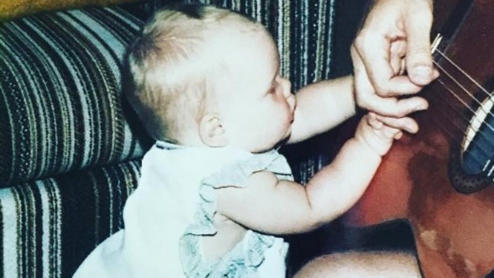Pink as a baby touching a guitar