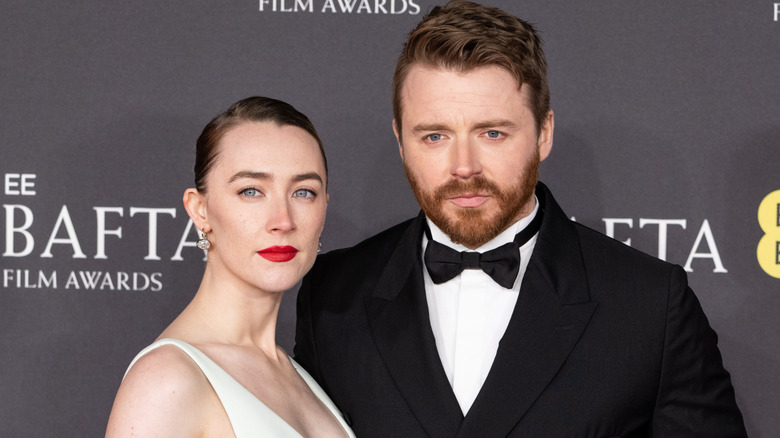 Saoirse Ronan and Jack Lowden smiling at the BAFTA Film Awards in 2025