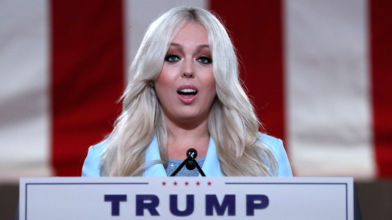 Tiffany Trump speaks at a podium with a Trump sign