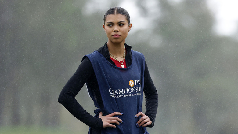 Sam Woods stands on the golf green as a teenager with her hands on her hips