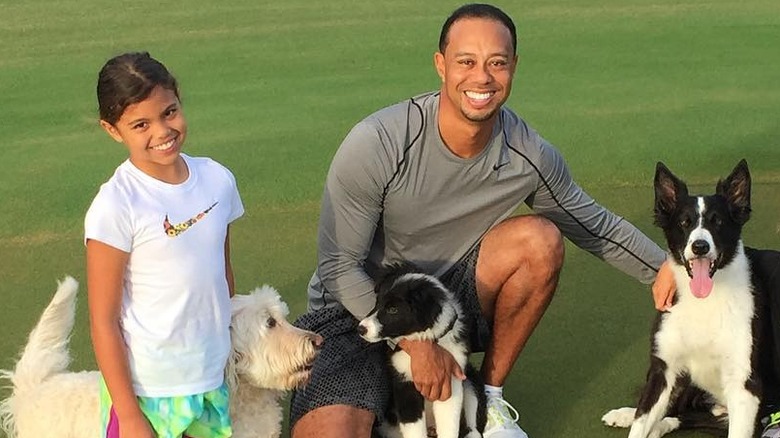 Tiger Woods' daughter Sam smiles on grass next to her dad and dogs