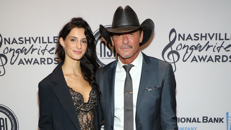 Audrey McGraw wearing a black lace bodysuit and posing next to Tim McGraw on the red carpet