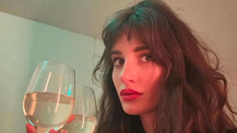 Audrey McGraw posing holding a glass of wine with her curly hair down