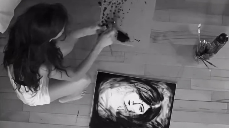 Audrey McGraw sitting on the floor next to a painting of a woman in a black and white photo